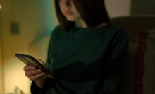A teen girl looks at her phone.